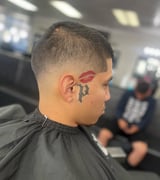 Side profile of person with short haircut and tattoos on neck and behind ear in a salon setting