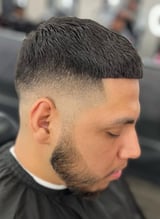 Profile view of man with modern fade haircut, short dark hair on top blending to shaved sides, with beard