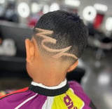 Close-up of childs fade haircut with geometric line designs on back of head in barbershop